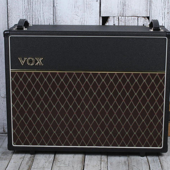 VOX guitar speaker cabinet with black frame and brown diamond grille on light wood floor